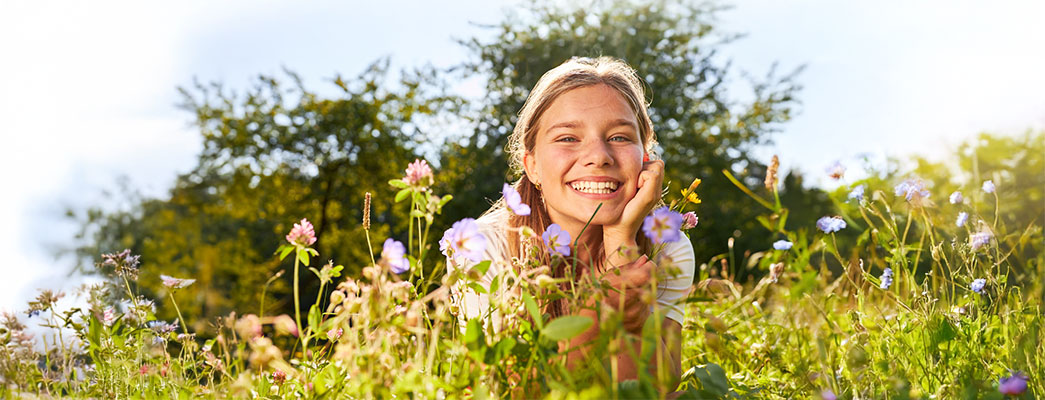Jugendliche liegt auf einer blühenden Blumenwiese