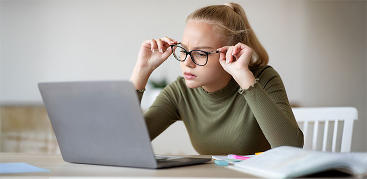 Junge Frau mit Brille schaut auf den Laptopbildschirm