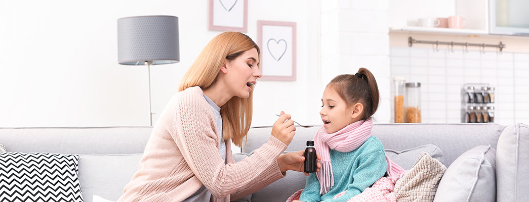 Mutter gibt erkälteter Tochter Hustensaft