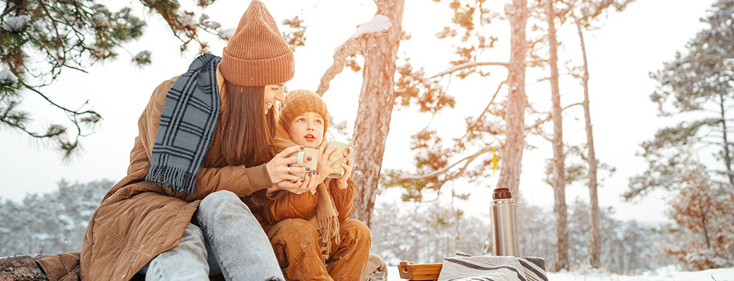 Mutter und Kind sitzen zusammen im Schnee