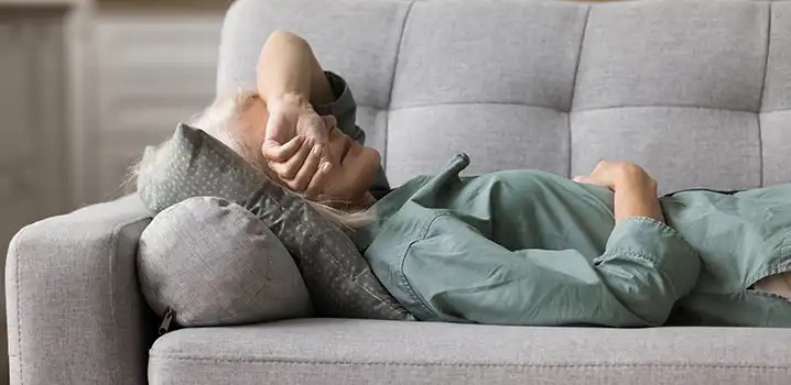 Frau liegt auf dem Sofa mit Hitzewallungen.