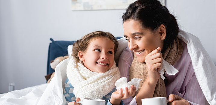 Mutter und Tochter kuscheln sich erkältet in eine Decke