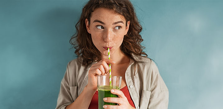 Junge Frau trinkt einen grünen Smoothie