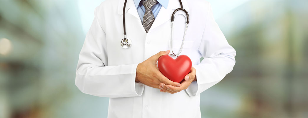 Person im Arztkittel die sich ein Herz vor die Brust hält