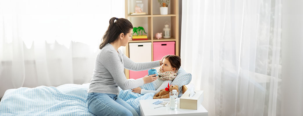 Mutter kümmert sich um kranke Tochter im Bett