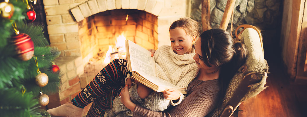 Mutter und Tochter lesend vor dem Kaminfeuer