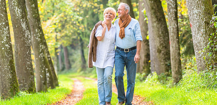 Älteres Ehepaar geht Arm in Arm im Wald spazieren