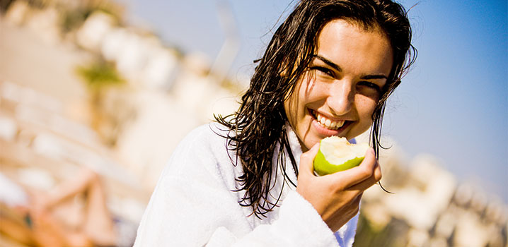 Frau im Bademantel beißt in einen Apfel