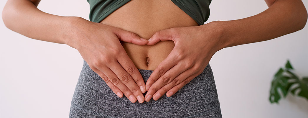 Frau formt mit den Händen ein Herz vor ihrem Bauch