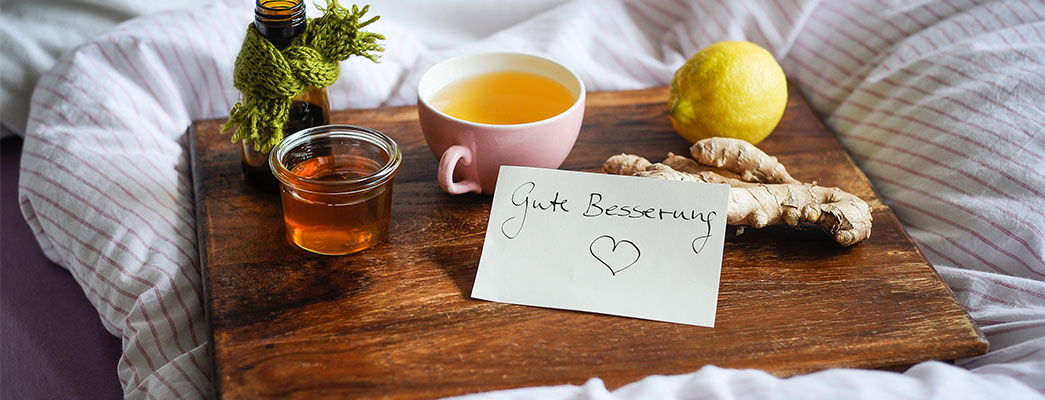 Tablett mit Tee, Medizin und Gute-Besserung-Schild