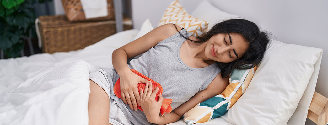 Frau mit Wärmflasche im Bett